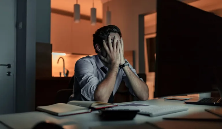 Homem estressado sentado em frente ao computador com as mãos no rosto(Foto: Canva)