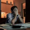Homem estressado sentado em frente ao computador com as mãos no rosto(Foto: Canva)